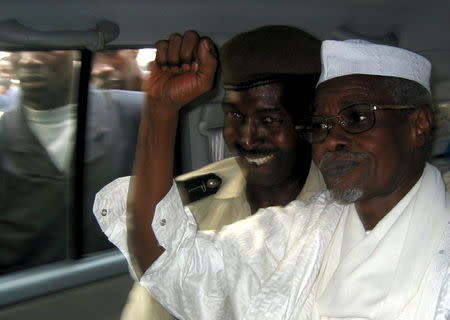 Former Chad President Hissene Habre (R) raises his fist in the air as he leaves a court in Dakar escorted by a Senegalese policeman in this November 25, 2005 file photo. REUTERS/Aliou Mbaye/Files