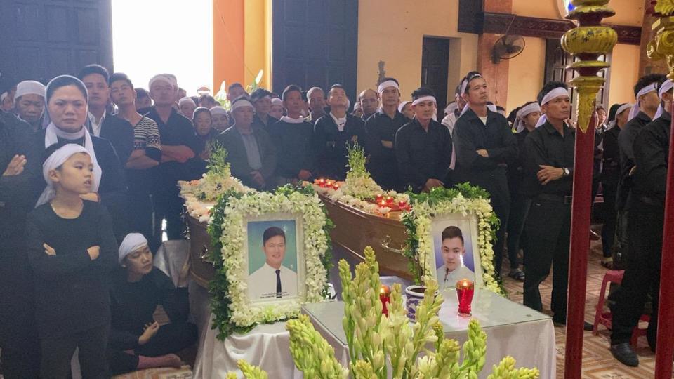 Relatives gather around the coffins of cousins Hoang Van Tiep and Nguyen Van Hung for a funeral ceremony in Trung Song church before their burial on Thursday, Nov. 28, 2019, in Dien Chau, Vietnam. Both Tiep and Hung were among the 39 Vietnamese who died when human traffickers carried them by truck to England in October, and whose remains were among the 16 repatriated to their homeland Wednesday. (AP Photo/Hau Dinh)