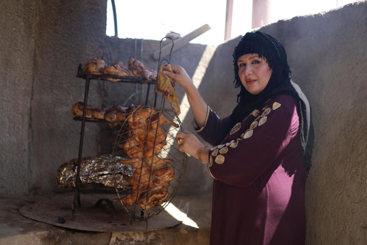 <span>Alhan al-Salmani, 50, with some of the food cooked in her kitchen’s tanoor, a traditional clay oven.</span><span>Photograph: Basim Ahmed Al-Dulaimi</span>