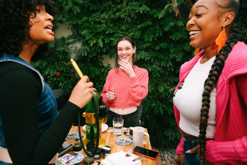 Los Angeles, CA - January 14: Friends Wilhelmina Simone, Montana Alexander and Leslie Jayy, right to left, smoke a bong together at the newly reopened Cannabis Cafe on Sunday, Jan. 14, 2024 in Los Angeles, CA. It was the first consumption lounge to open in 2019 and then closed for three years during the pandemic. (Dania Maxwell / Los Angeles Times)