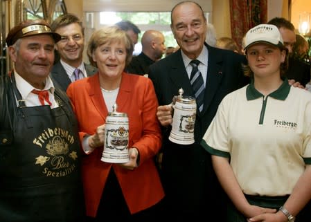 FILE PHOTO: German Chancellor Merkel and French President Chirac pose with waiters during their summit in Rheinsberg