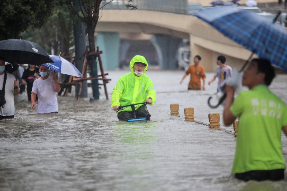 This photo taken on July 20, 2021 shows a man riding a bicycle through flood waters along a street following heavy rains in Zhengzhou in China's central Henan province. - - China OUT (Photo by STR / AFP) / China OUT (Photo by STR/AFP via Getty Images)