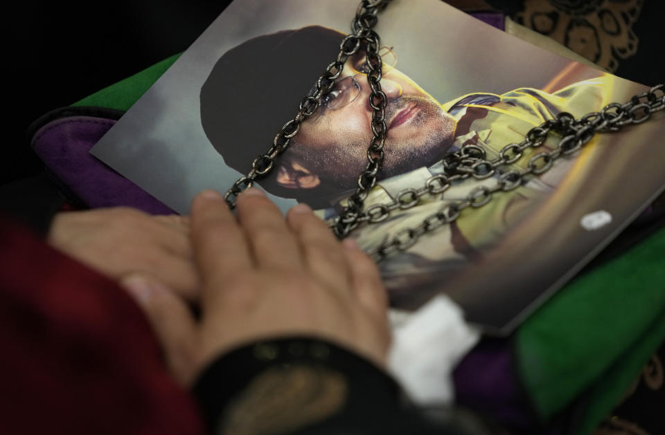 A Hezbollah supporter carries a portrait of Hezbollah slain top commander Mustafa Badreddine, who was killed in Syria, as they listen to Hezbollah leader Sayyed Hassan Nasrallah during a ceremony to mark the seven anniversary of his death, in the southern suburbs of Beirut, Lebanon, Friday, May 12, 2023. Nasrallah denied reports that linked one of Syria's most well-known drug dealers who was killed earlier this week in an airstrike near the Jordanian border to the Iran-backed group calling such accusations "baseless lies." (AP Photo/Hussein Malla)