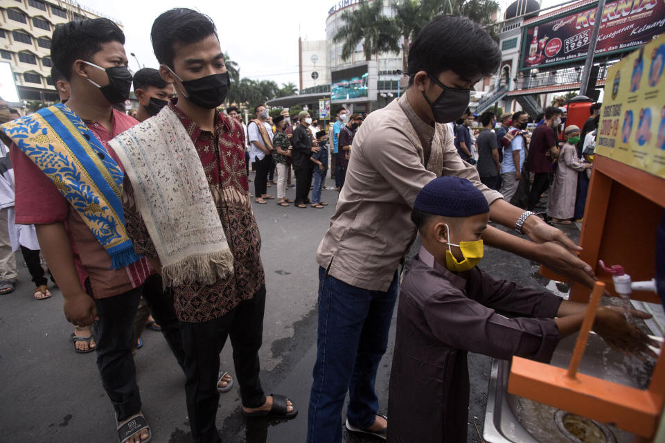 Muslim men queue up to wash their hands prior to entering Al Mashun Grand Mosque's compound to attend an Eid al Fitr prayer amid concerns of coronavirus outbreak in Medan, North Sumatra, Indonesia, Sunday, May 24, 2020. Millions of people in the world's largest Muslim nation are marking a muted and gloomy religious festival of Eid al-Fitr, the end of the fasting month of Ramadan - a usually joyous three-day celebration that has been significantly toned down as coronavirus cases soar. (AP Photo/Binsar Bakkara)