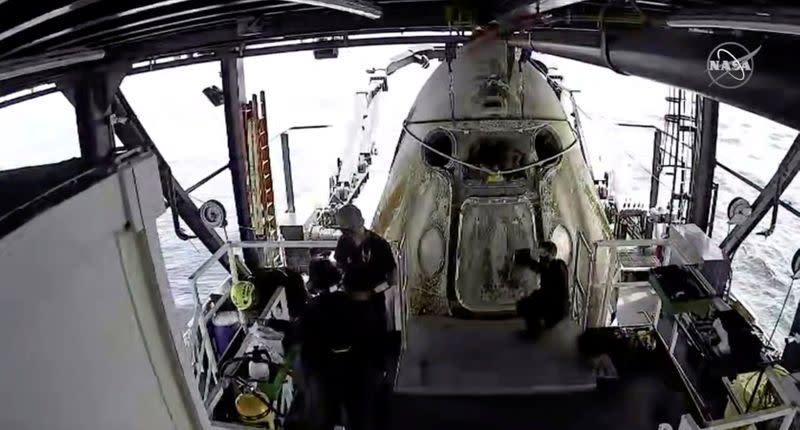 Engineers do a purge of vapor fumes around the Dragon Endeavour with NASA astronauts Robert Behnken and Douglas Hurley aboard after the capsule splashed down in the Gulf of Mexico