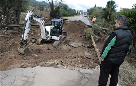 Labourers work to clear a damaged road of debris following extreme rainfall near Olbia on Sardinia island November 20, 2013. REUTERS/Tony Gentile