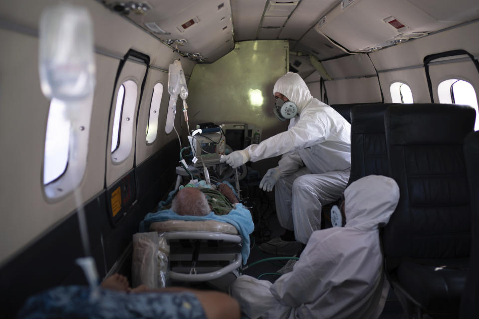 Doctor Daniel Siqueira, top, and nurse Janete Vieira monitor 89-year-old COVID-19 patient Sildomar Castelo Branco onboard an aircraft, as he is transferred from Santo Antonio do Iça to a hospital in Manaus, Brazil, Tuesday, May 19, 2020. (AP Photo/Felipe Dana)