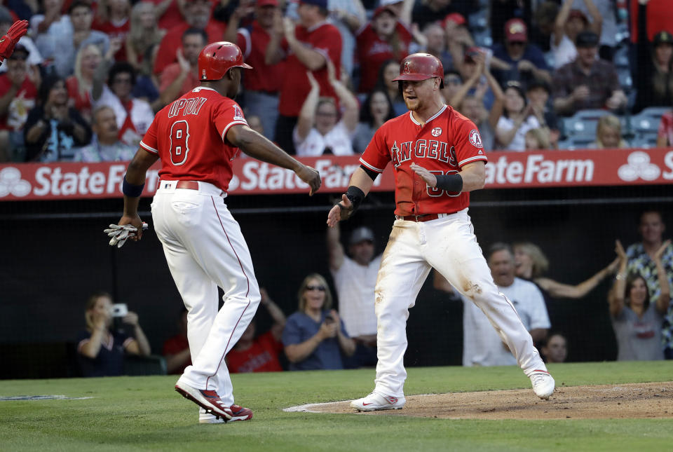 Los Angeles Angels' Kole Calhoun, right, celebrates with Justin Upton (8) after they scored on a double by Albert Pujols during the first inning of a baseball game against the Houston Astros on Tuesday, July 16, 2019, in Anaheim, Calif. (AP Photo/Marcio Jose Sanchez)