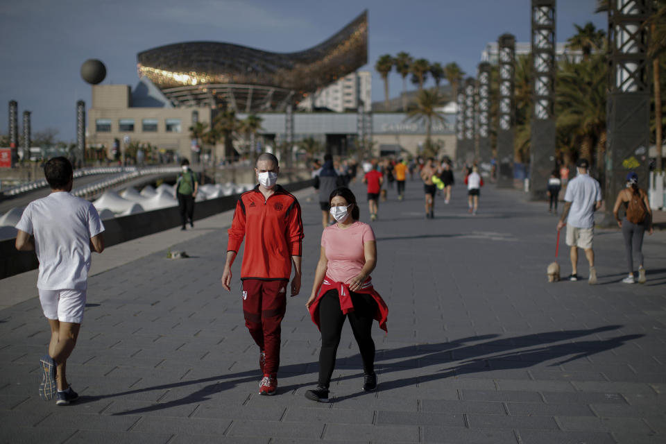 People walk along a seafront promenade in Barcelona, Spain, Saturday, May 2, 2020. Spaniards have filled the streets of the country to do exercise for the first time after seven weeks of confinement in their homes to fight the coronavirus pandemic. People ran, walked, or rode bicycles under a brilliant sunny sky in Barcelona on Saturday, where many flocked to the maritime promenade to get as close as possible to the still off-limits beach. People are supposed to respect a 1-measure distance, but the crowds in some spots made that impossible. (AP Photo/Emilio Morenatti)