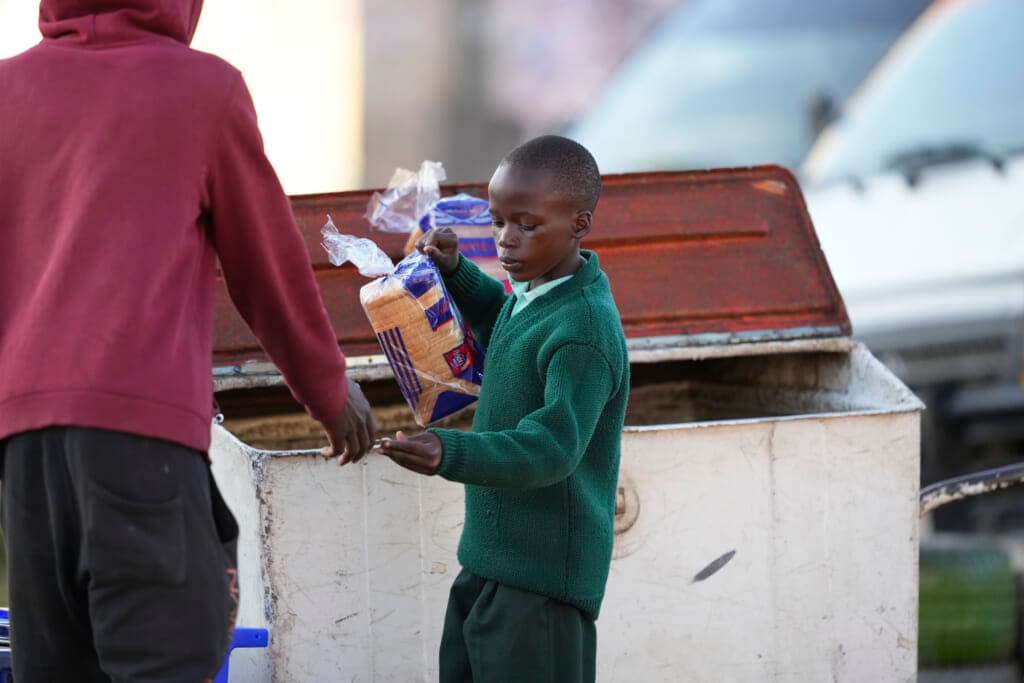 A young boy buys a loaf of bread from a street vendor in Harare, Zimbabwe, Monday, May, 23, 2022. Rampant inflation is making it increasingly difficult for people in Zimbabwe to make ends meet. (AP Photo/Tsvangirayi Mukwazhi)