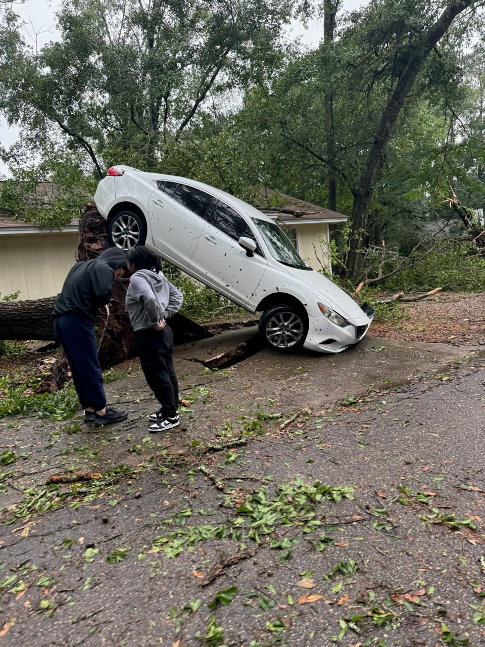 An uprooted tree pulled up the pavement and tilted a car along Tomahawk Trail Friday May 10, 2024