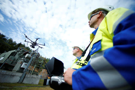 Workers operate a drone to survey high-voltage power lines of electric company Westnetz near Wilnsdorf, Germany, July 11, 2018. REUTERS/Ralph Orlowski