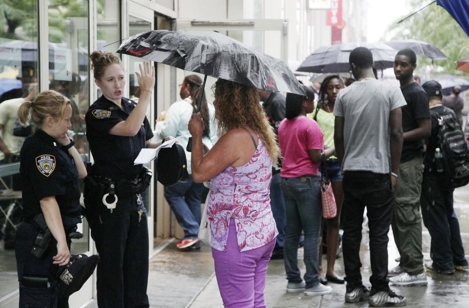 New York City police officers stand in front of a midtown Manhattan movie theater as people arrive for a screening of "The Dark Knight Rises," Friday, July 20, 2012 in New York. A gunman in a gas mask barged into a crowded Denver-area theater during a midnight premiere of the Batman movie on Friday, hurled a gas canister and then opened fire, killing 12 people and injuring at least 50 others in one of the deadliest mass shootings in recent U.S. history. NYPD commissioner Ray Kelly said the department was providing the extra security at theaters "as a precaution against copycats and to raise the comfort levels among movie patrons." (AP Photo/Mark Lennihan)