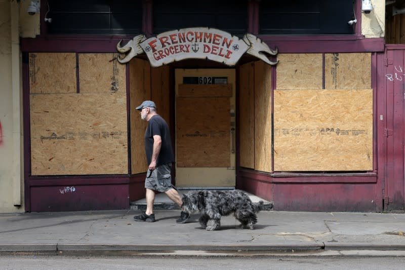 A man walks his dog past a boarded up business on Frenchmen Street, following the outbreak of the coronavirus disease (COVID-19), in New Orleans