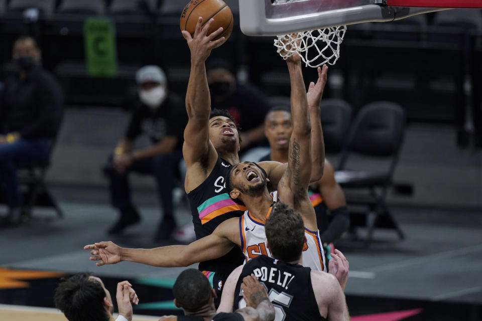 San Antonio Spurs forward Keldon Johnson, rear, reaches over Phoenix Suns guard Cameron Payne, center, for a rebound during the first half of an NBA basketball game in San Antonio, Sunday, May 16, 2021. (AP Photo/Eric Gay)