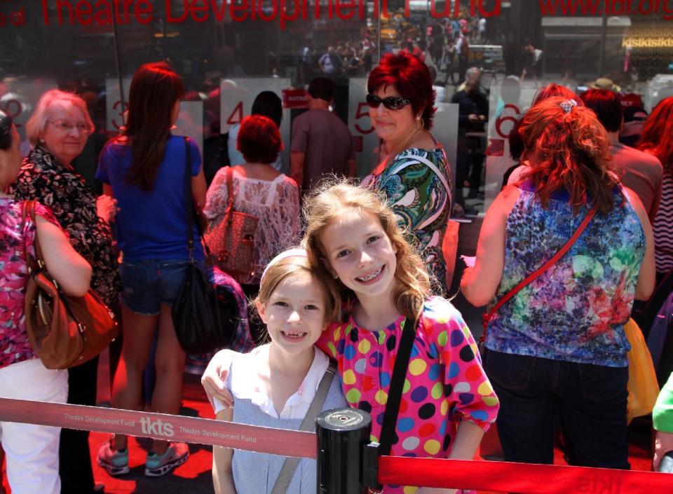 This June 19, 2013 photo shows Maggie Patrick, 7, left, and her sister Sophie Patrick, 9, outside the famous TKTS booth in Times Square in New York. The girls were there after school with family members to get discount tickets to a matinee. (AP Photo/Mark Kennedy)