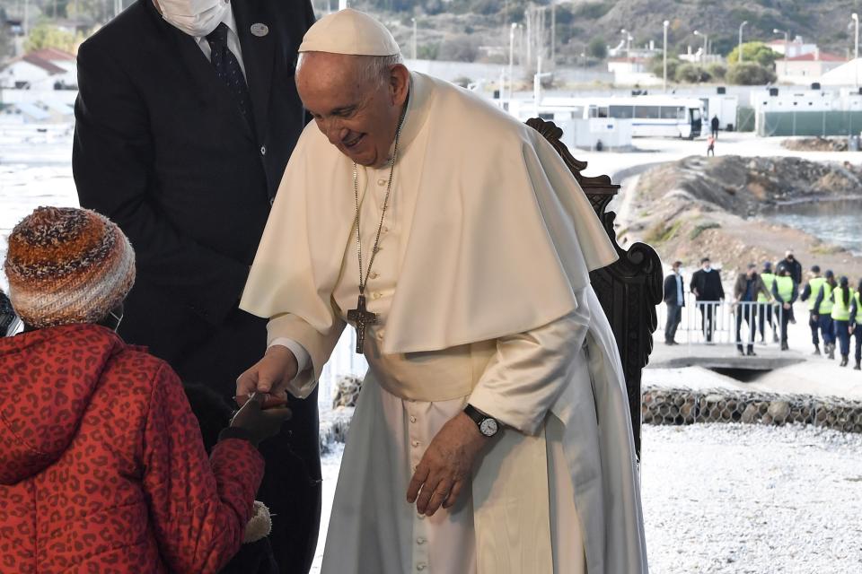 Pope Francis meets a child during a ceremony at the Karatepe refugee camp, on the northeastern Aegean island of Lesbos, Greece, Sunday, Dec. 5, 2021. Pope Francis is offering comfort migrants at a refugee camp on the Greek island of Lesbos. He is blasting what he says is the indifference and self-interest shown by Europe "that condemns to death those on the fringes." (Louisa Gouliamaki/Pool via AP)