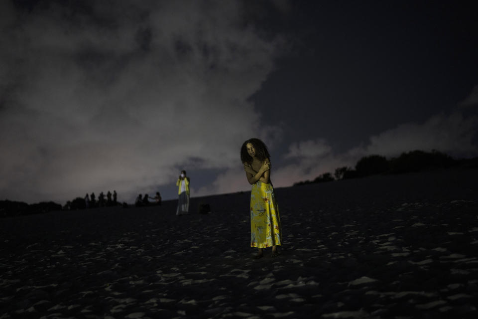 Una mujer reza en una zona del sistema de dunas de Abaete, en una elevación de arena que los evangélicos han empezado a llamar Montaña Sagrada en Salvador, Brasil, la noche del viernes 16 de septiembre de 2022. (AP Foto/Rodrigo Abd)