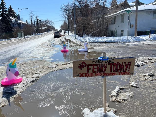 Jamie Ruff brought signs and floaties to an intersection near his home in Marda Loop Friday, bringing attention to a blocked storm drain. (Submitted by Jamie Ruff - image credit)