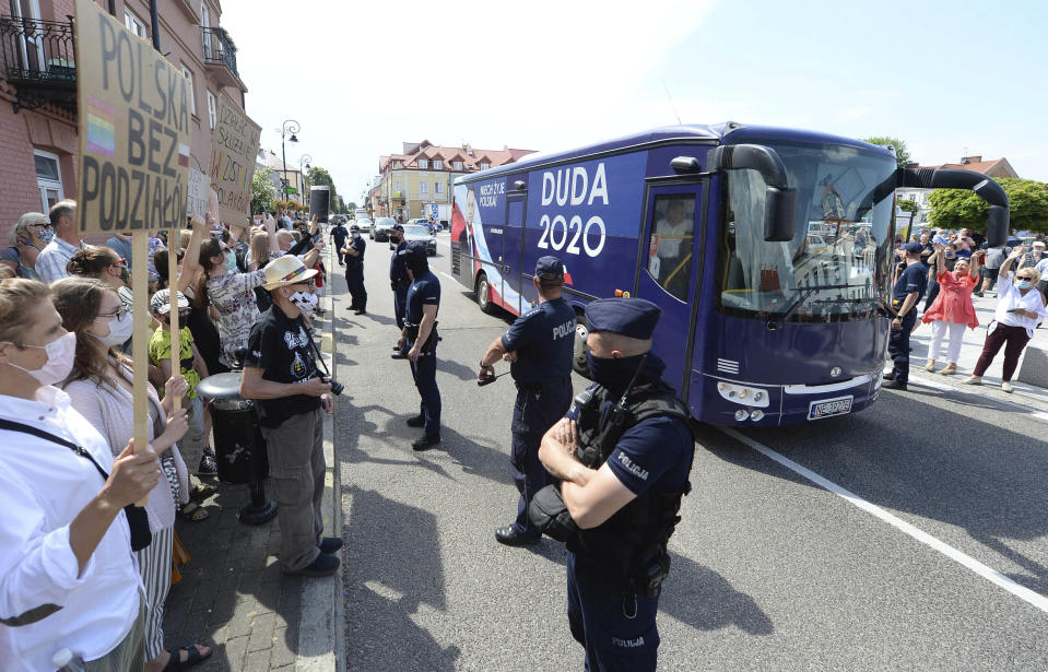 ARCHIVO - En esta imagen del 17 de junio de 2020, manifestantes proLGTB protestan a la llegada del autobús de campaña del presidente de Polonia, Andrzej Duda, en Serock, Polonia. Duda, que ha descrito varias veces al movimiento de derechos LGTB como “ideología” peligrosa, asume su segundo mandato el jueves. Algunos polacos gays, lesbianas, bisexuales y trans emigraron para escapar de lo que consideran homofobia fomentada desde los más altos niveles del gobierno. (AP Foto/Czarek Sokolowski/archivo)