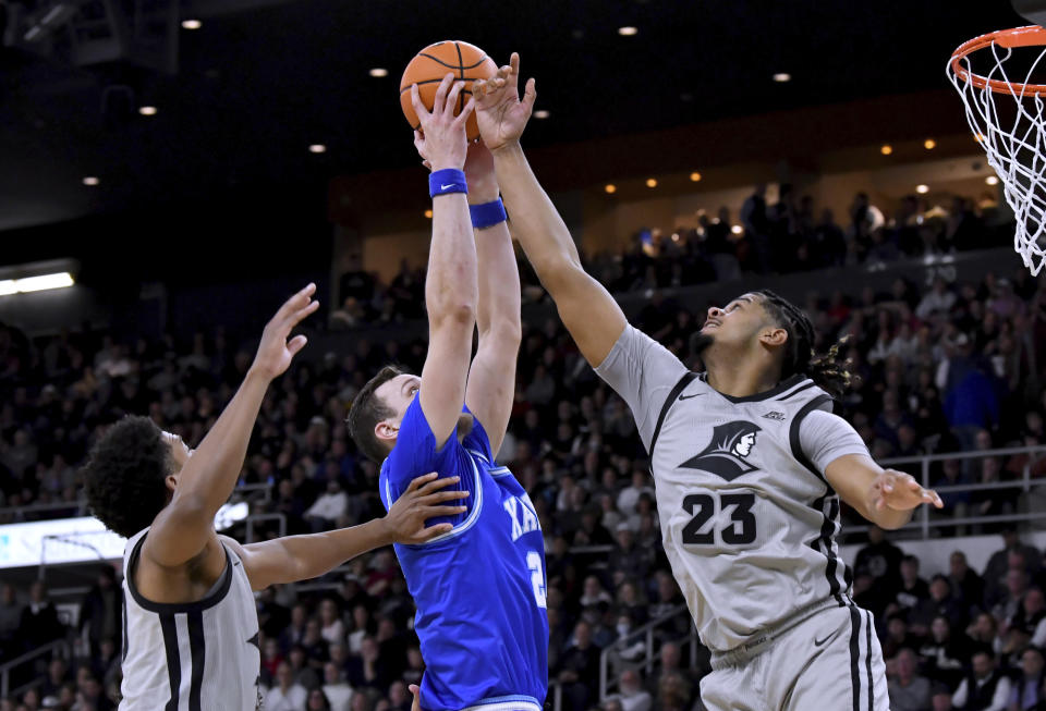 Providence guard Noah Locke, left, and forward Bryce Hopkins (23) defend against a shot by Xavier forward Jack Nunge (24) during the first half of an NCAA college basketball game Wednesday, March 1, 2023, in Providence, R.I. (AP Photo/Mark Stockwell)