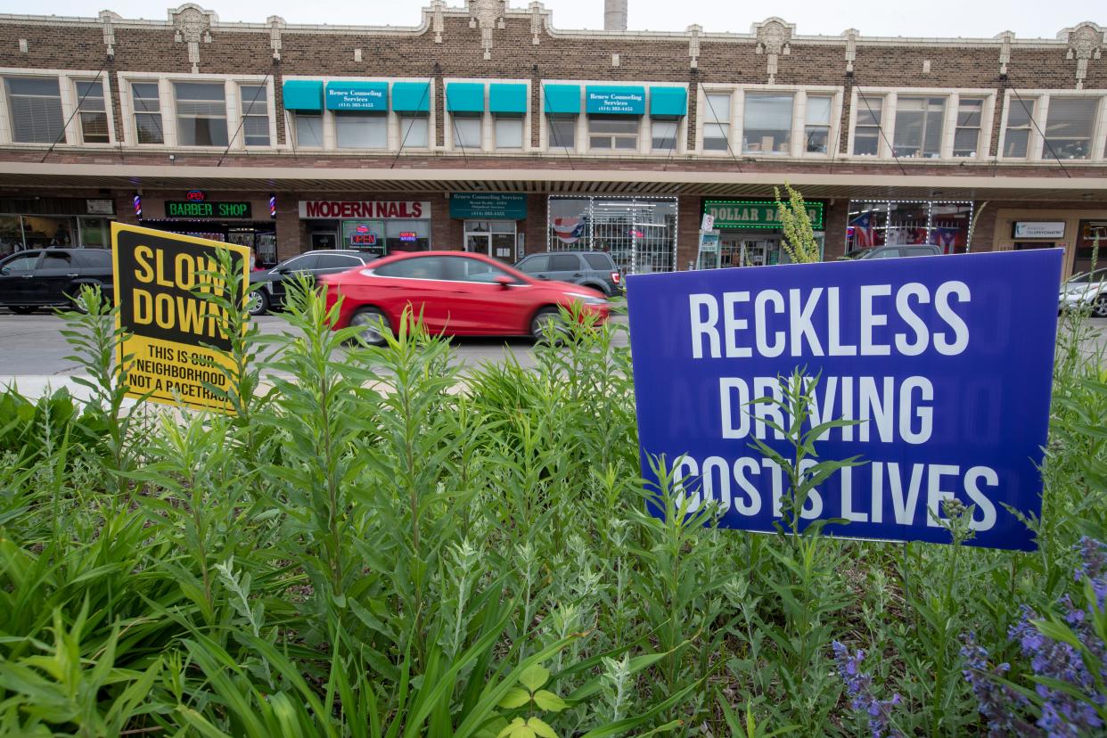 Two signs in the median in Milwaukee encourage drivers to slow down.