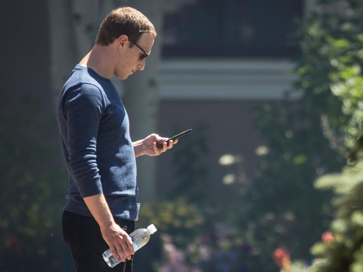 Facebook CEO Mark Zuckerberg looks at his phone.