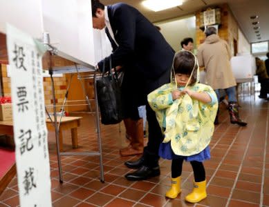 A girl stands next to her father filling out his ballot for a national election at a polling station in Tokyo, Japan October 22, 2017. REUTERS/Kim Kyung-Hoon