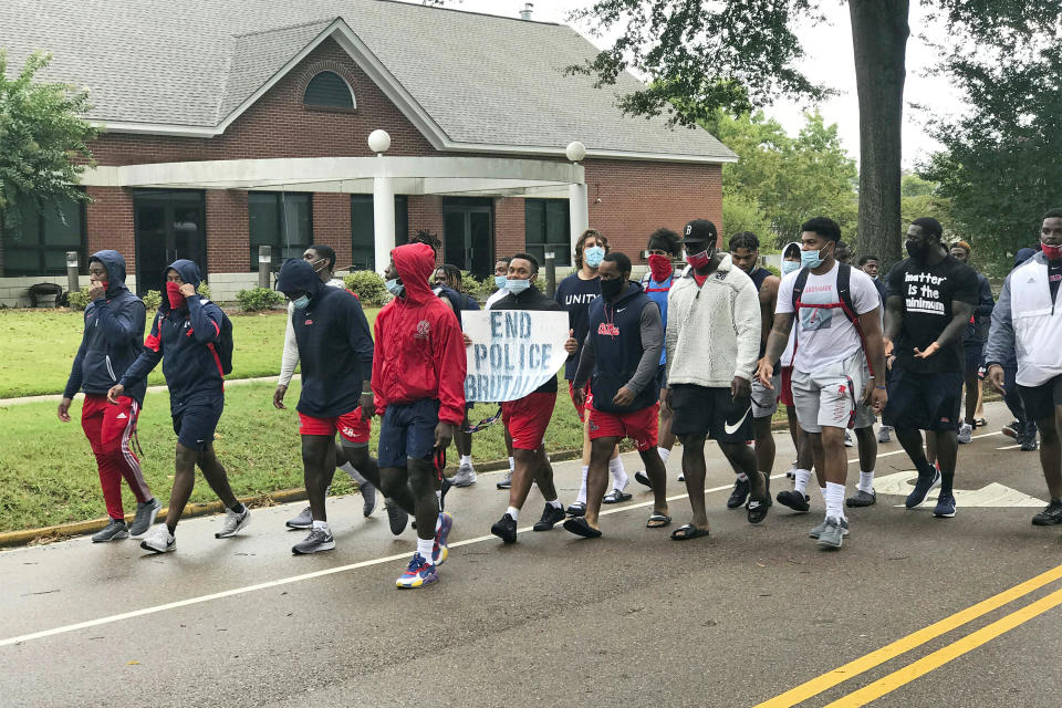 Mississippi football players, wearing face masks, march from the town square back to the University of Mississippi campus after boycotting morning practice for the upcoming NCAA college football season, Friday, Aug. 28, 2020, Oxford, Miss. The boycott was in the wake of the shooting of a Wisconsin man, Jacob Blake who is Black, by a police officer earlier this month. (Jake Thompson/The Oxford Eagle via AP)