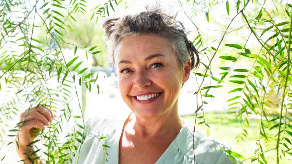 A woman with grey hair outdoors smiling