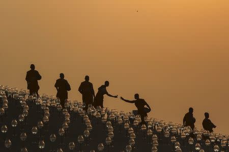 Buddhist monks prepare for an alms offering ceremony at the Wat Phra Dhammakaya temple in Pathum Thani province, north of Bangkok as the sun rises on Makha Bucha Day, in this March 4, 2015 file photo. REUTERS/Damir Sagolj/Files