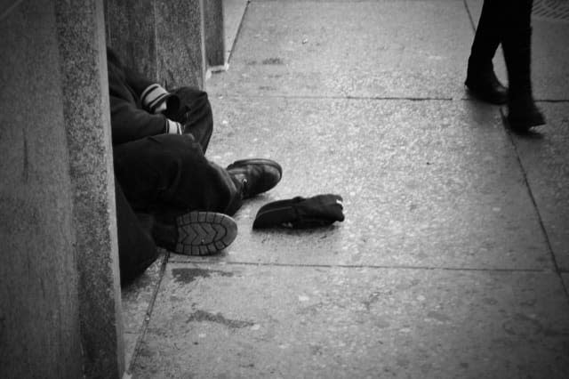 Homeless person sitting on road.