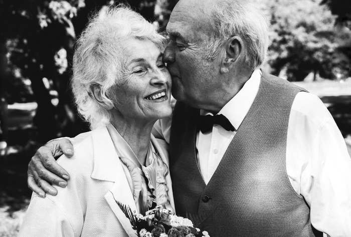 An older man kissing and hugging a smiling older woman