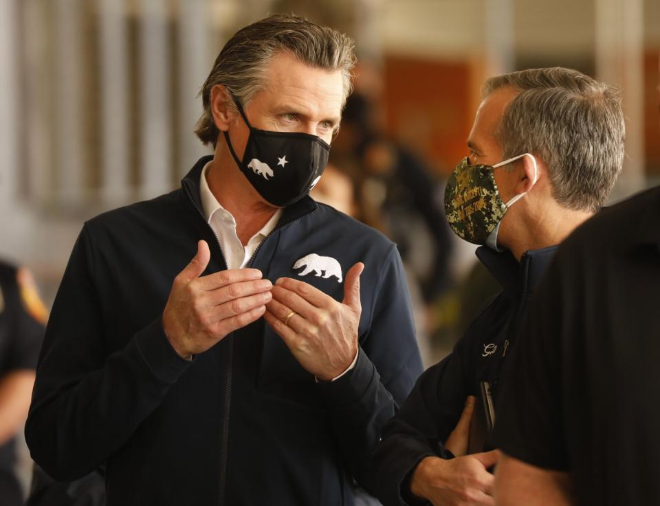 Gov. Gavin Newson, left, and Los Angeles Mayor Eric Garcetti, right, talk during a news conference at Cal State Los Angeles