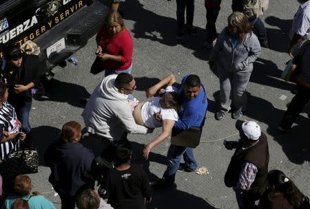 People help a woman who fainted while standing with family members of inmates outside the Topo Chico prison in Monterrey, Mexico, February 11, 2016. REUTERS/Daniel Becerril