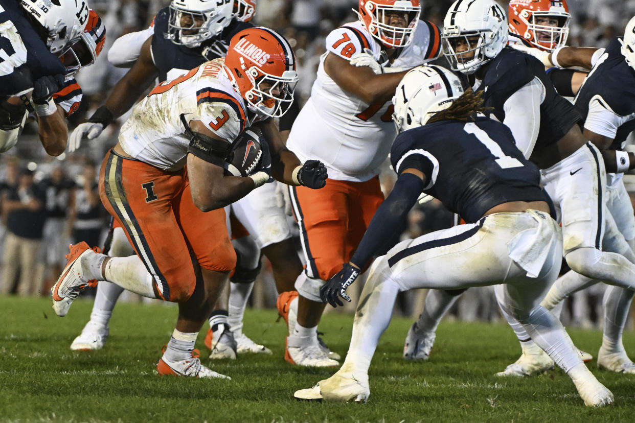 Illinois running back Kaden Feagin (3) runs with the ball while pressured by Penn State safety Jaylen Reed (1) during the second quarter of an NCAA college football game, Saturday, Sept. 28, 2024, in State College, Pa. (AP Photo/Barry Reeger)