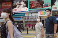 People walk past a TV screen showing the closing session of the National People's Congress (NPC) in Beijing where voting on the national security legislation for Hong Kong took place, in Hong Kong