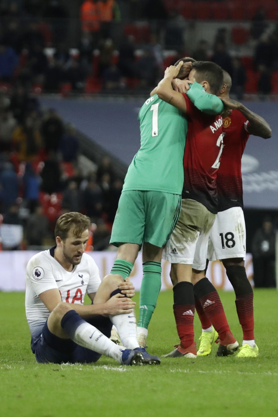 Tottenham's Harry Kane sits on the pitch with an injury as Manchester United players hugs teammate and goalkeeper David de Gea, left in green, after the English Premier League soccer match between Tottenham Hotspur and Manchester United at Wembley stadium in London, England, Sunday, Jan. 13, 2019. (AP Photo/Matt Dunham)