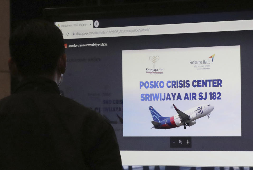 A man stands near an LCD screen installed at a crisis center set up following a report that a Sriwijaya Air passenger jet has lost contact with air traffic controllers after take off, at Soekarno-Hatta International Airport in Tangerang, Indonesia,Saturday, Jan. 9, 2021. A Sriwijaya Air passenger jet with 56 passengers and six crew members onboard, lost contact with air traffic controllers after taking off from Indonesia's capital on Saturday on a domestic flight, officials said. (AP Photo/Tatan Syuflana)