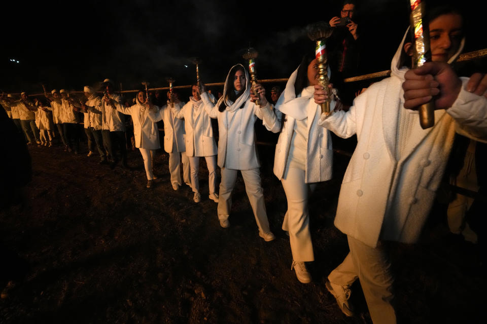 Iranian Zoroastrian youth join hands after setting a prepared pile of wood on fire as they celebrate their ancient mid-winter Sadeh festival in the outskirts of Tehran, Iran, Tuesday, Jan. 30, 2024. Hundreds of Zoroastrian minorities gathered after sunset to mark their ancient feast, creation of fire, dating back to Iran's pre-Islamic past. (AP Photo/Vahid Salemi)