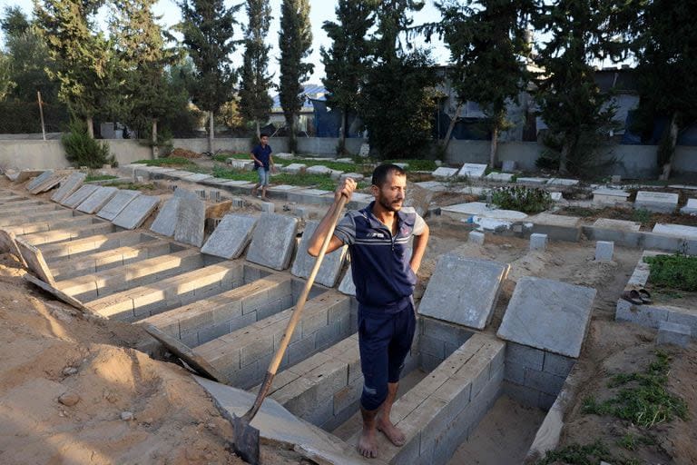Un hombre descansa sobre una fila de tumbas recién construidas en Rafah, en el sur de la Franja de Gaza, el 10 de noviembre de 2023, en medio de batallas en curso entre Israel y el grupo palestino Hamas. 