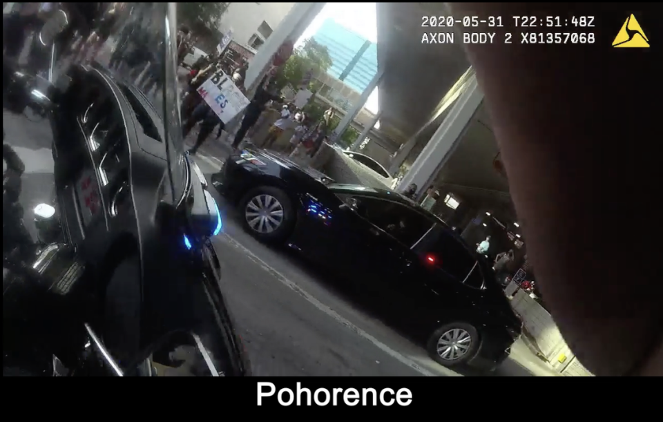 A body camera worn by Officer Steven Pohorence shows the moment officer Stylianee Hayes reported protesters jumping on the trunk of her black Toyota Camry. No one is visible near the vehicle.