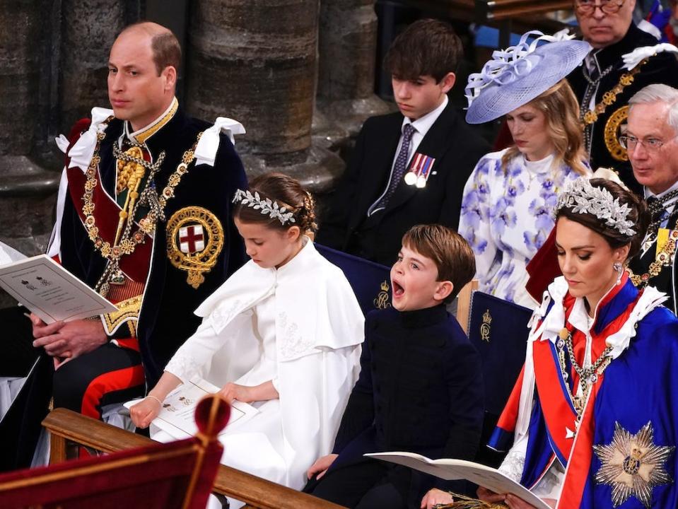Prince Louis yawns in his seat at Westminster Abbey during King Charles' coronation, seated with his mother Kate Middleton, sister Princess Charlotte, and father Prince William.