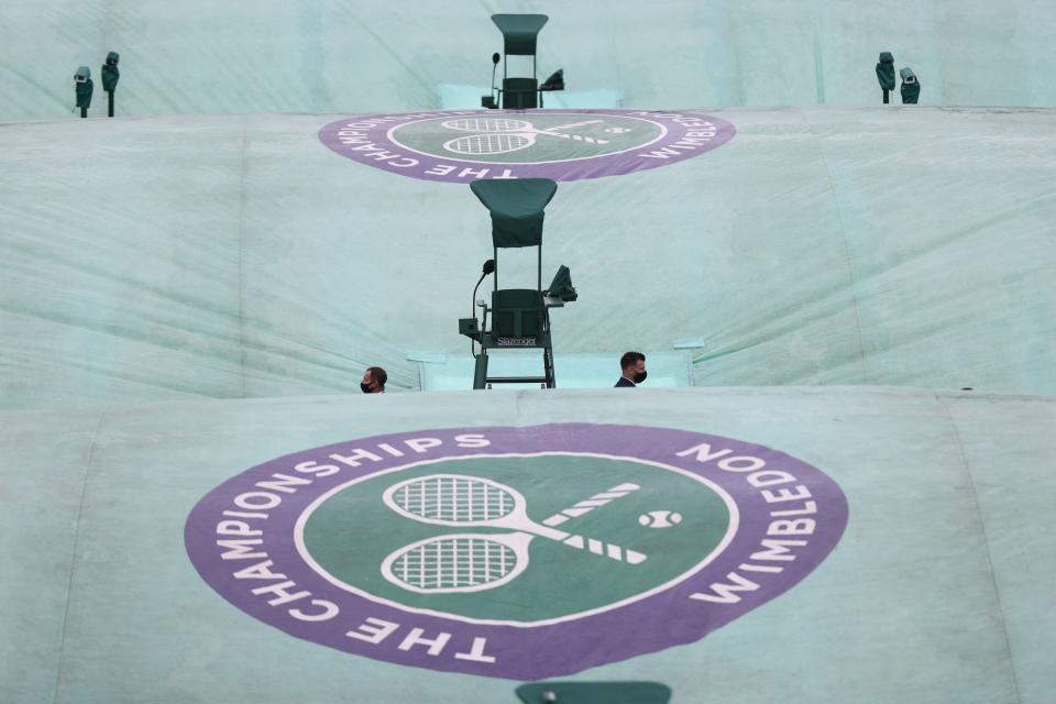<p>Security guards are seen in the middle of rain covers on an outside court on the first day of the 2021 Wimbledon Championships at the The All England Tennis Club in Wimbledon, southwest London, on June 28, 2021. - RESTRICTED TO EDITORIAL USE (Photo by Adrian DENNIS / AFP) / RESTRICTED TO EDITORIAL USE (Photo by ADRIAN DENNIS/AFP via Getty Images)</p>
