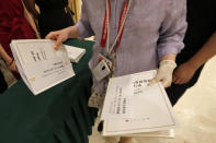 A journalist wearing a protective glove collects copies of the white paper on China's fighting of the Covid-19 coronavirus before a press conference at the State Council Information Office in Beijing, Sunday, June 7, 2020. Senior Chinese health officials defended their country's response to the new coronavirus pandemic, saying they provided information in a timely and transparent manner. (AP Photo/Andy Wong)