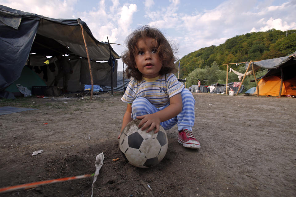 In this photo taken on Monday, Aug. 13, 2018, Shilla from Iran plays with a ball in a makeshift migrant camp in Velika Kladusa, 500 kms northwest of Sarajevo, Bosnia. Impoverished Bosnia must race against time to secure proper shelters for at least 4,000 migrants and refugees expected to be stranded in its territory during coming winter. The migrant trail shifted toward Bosnia as other migration routes to Western Europe from the Balkans were closed off over the past year. (AP Photo/Amel Emric)