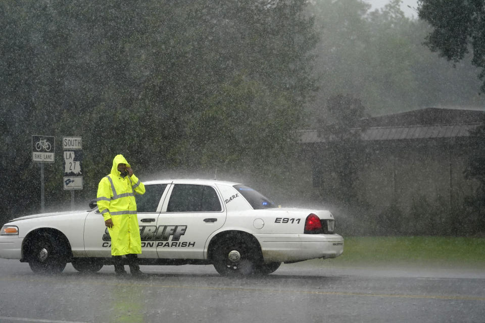 Un policía del municipio de Cameron se limpia el rostro mientras dirige un control carretero bajo la lluvia en la autopista LA 27 mientras residentes evacuan la localidad de Cameron, en Lake Charles, Luisiana, el miércoles 26 de agosto de 2020, en anticipación a la llegada del huracán Laura. (AP Foto/Gerald Herbert)