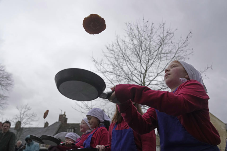 Schoolchildren from local schools take part in the children's races prior to the annual Pancake race in the town of Olney, in Buckinghamshire, England, Tuesday, Feb. 13, 2024. Every year women clad in aprons and head scarves from Olney and the city of Liberal, in Kansas, USA, run their respective legs of the race with pancakes in their pans. According to legend, the Olney race started in 1445 when a harried housewife arrived at church on Shrove Tuesday still clutching her frying pan with a pancake in it. (AP Photo/Kin Cheung)