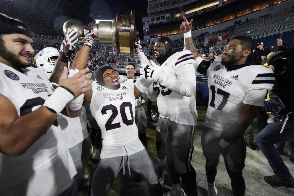 Mississippi State cornerback Alexander Shaw (20) hoists the Egg Bowl trophy amid teammates following an NCAA college football game win over Mississippi in Oxford, Miss., Thursday, Nov. 24, 2022. (AP Photo/Rogelio V. Solis)