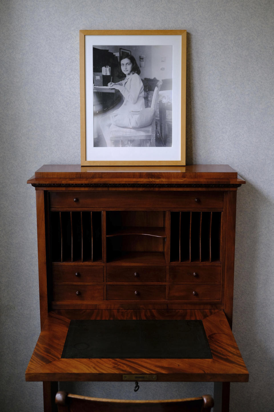 FILE - A photo of Anne Frank stands on a replica of the writing desk she once used in her family's former apartment in Amsterdam, during an event to mark what would have been Anne Frank's 90th birthday, in Amsterdam, Netherlands, Wednesday, June 12, 2019. A group of Dutch historians has published an in-depth criticism of the work and conclusion of a cold case team that said it had pieced together the “most likely scenario” of who betrayed Jewish teenage diarist Anne Frank and her family. (AP Photo/Michael C. Corder, File)